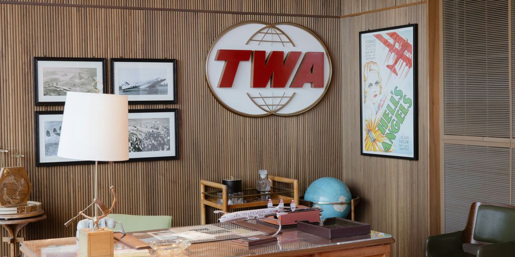 a room with a desk, chair, lamp and pictures on the wall