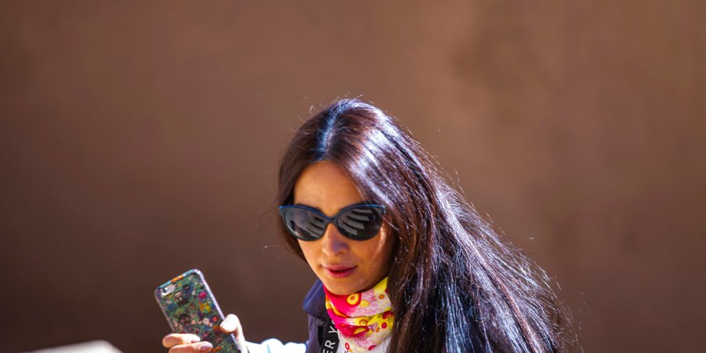 woman in white and pink jacket holding iphone