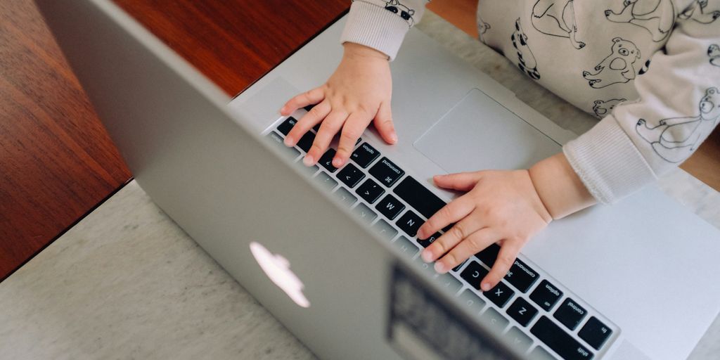 a young child is typing on a laptop
