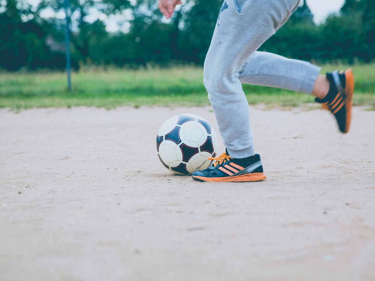 person plays soccer ball on white sands