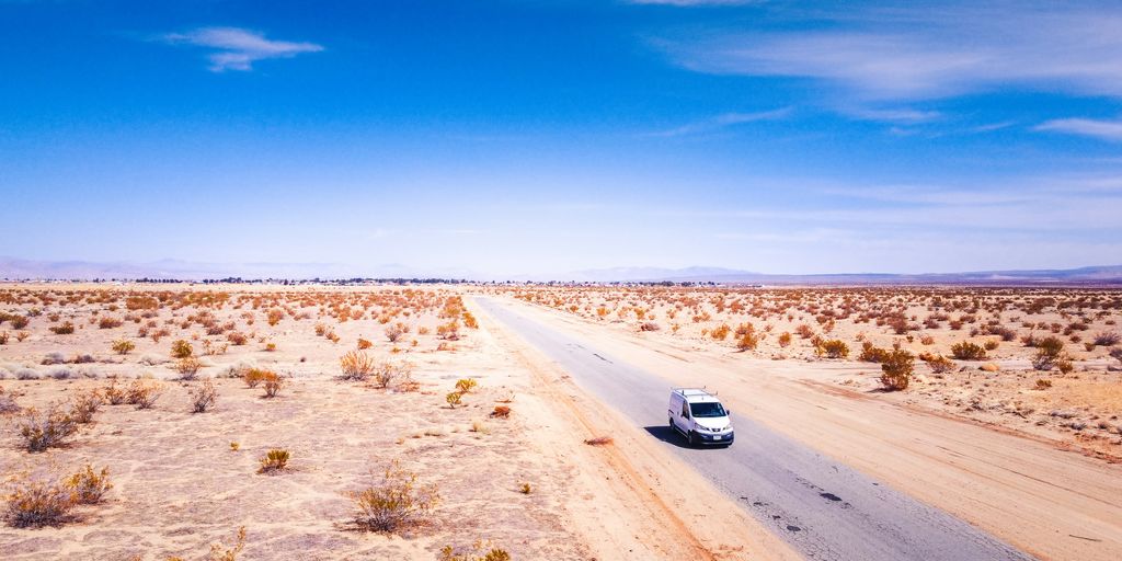white car on brown field under blue sky during daytime