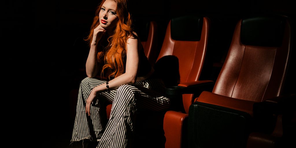 a woman with red hair sitting in a theater