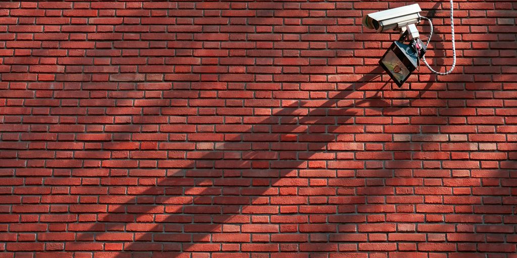 gray CCTV camera beside red bricked wall