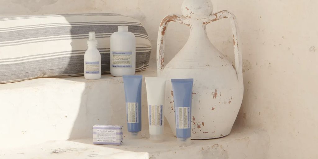 Sunscreen products and a ceramic jug on a shelf.