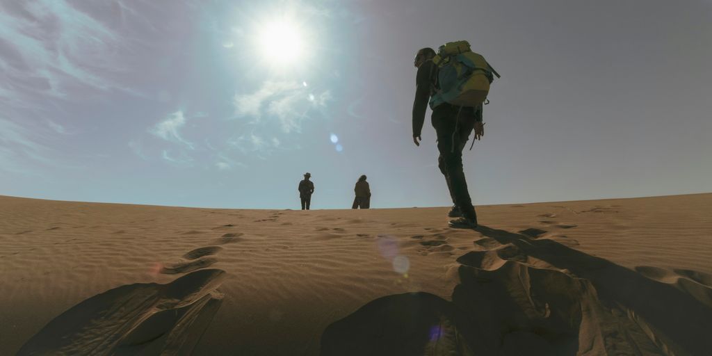 a group of people walking across a sandy field