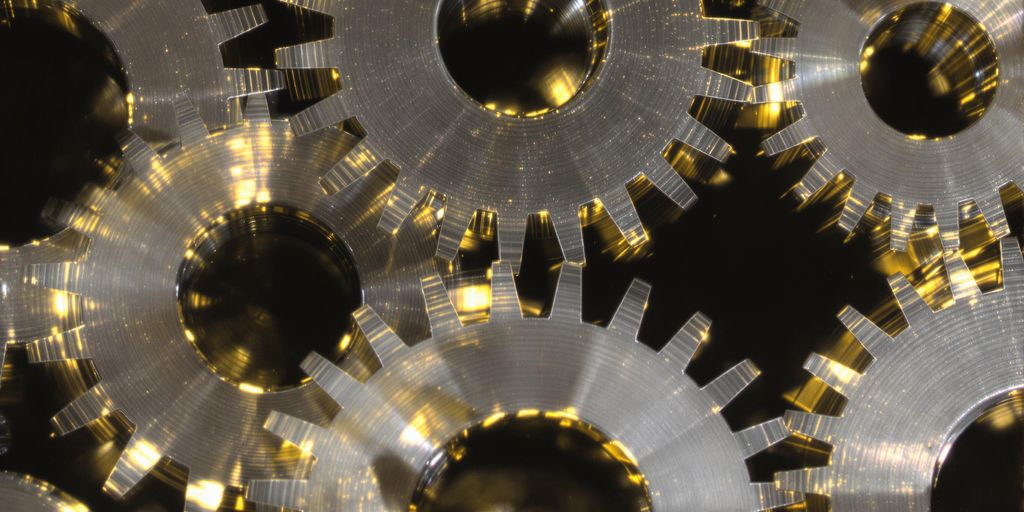 Gears turning, fitting together, glowing, on dark background.