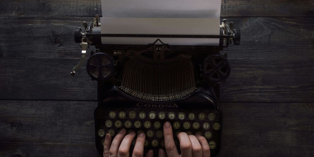 person holding white and black typewriter