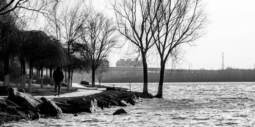 a man walking down a sidewalk next to a body of water