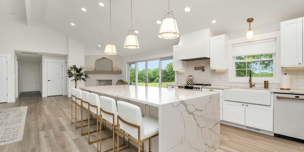 a large kitchen with a marble island and white cabinets