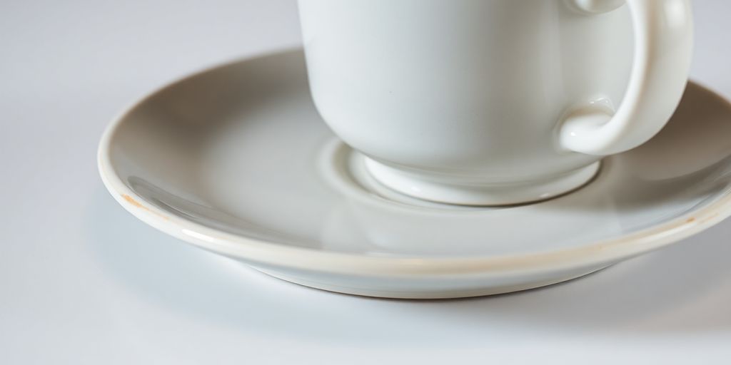 Soucoupe en faïence avec une tasse de café posée dessus.