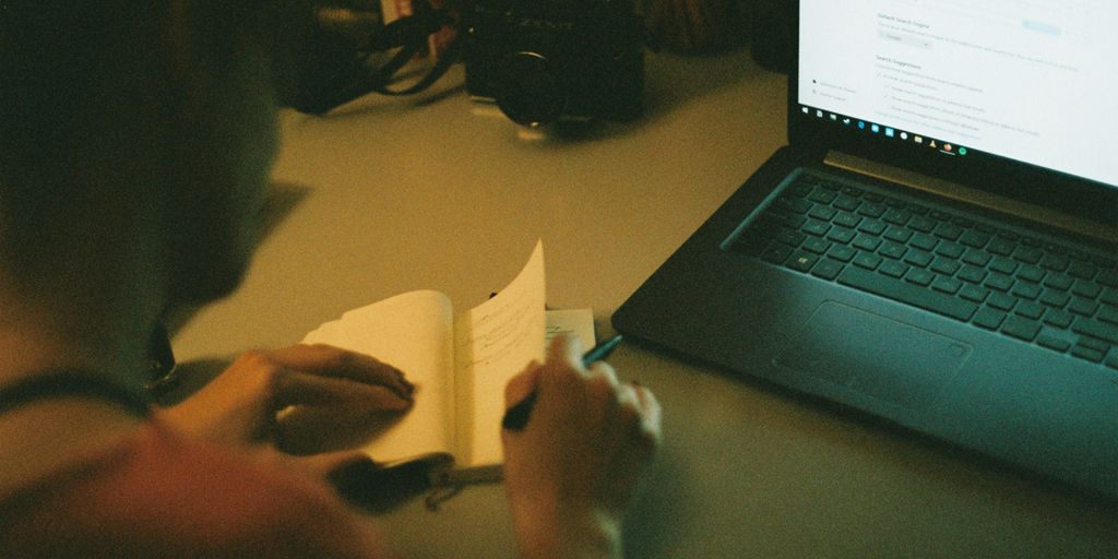 person holding white paper near black laptop computer