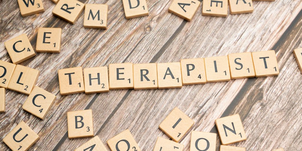 scrabble tiles spelling out the word therapy on a wooden surface