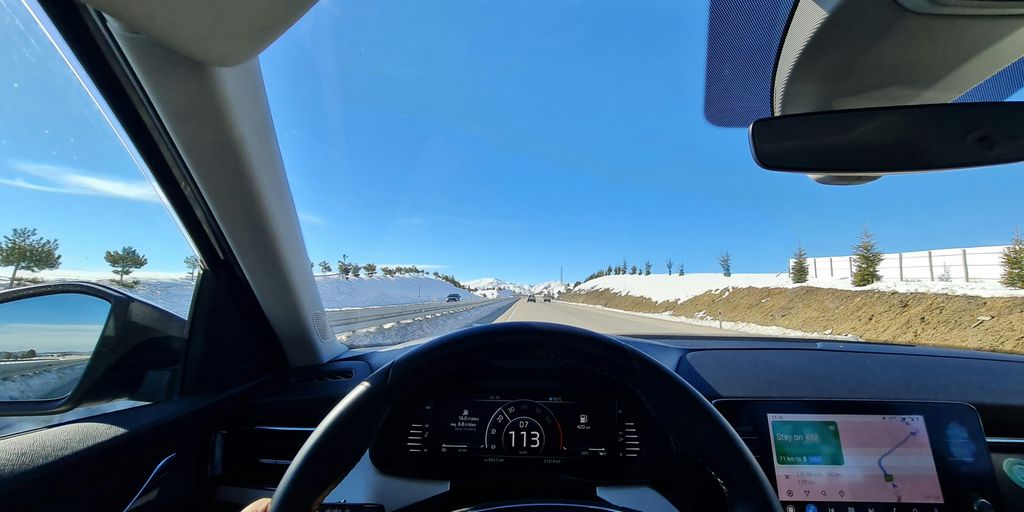 a car driving down a road next to a snow covered hillside