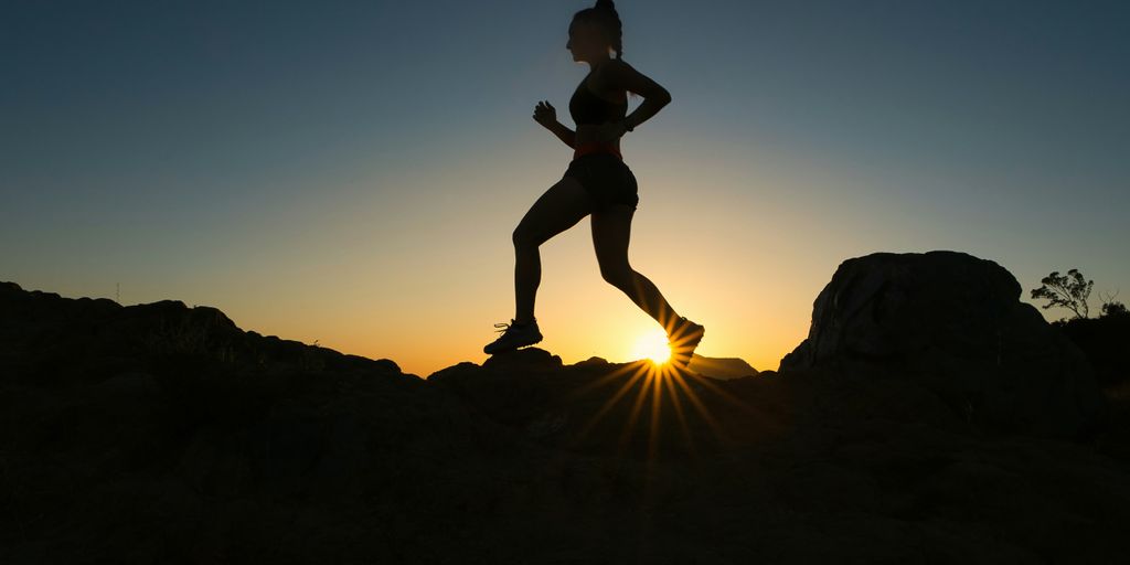 silhouette of man jumping on rocky mountain during sunset