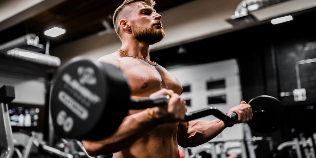 topless man in black shorts carrying black dumbbell