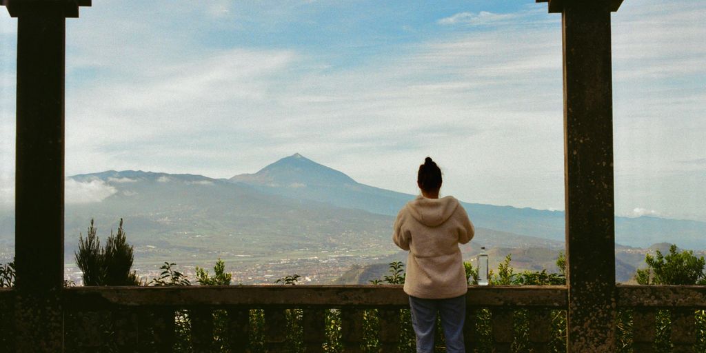 a woman standing on a balcony looking at a mountain