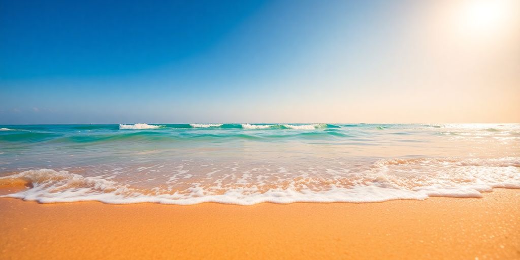 Golden sand beach with calm turquoise water and clear sky.