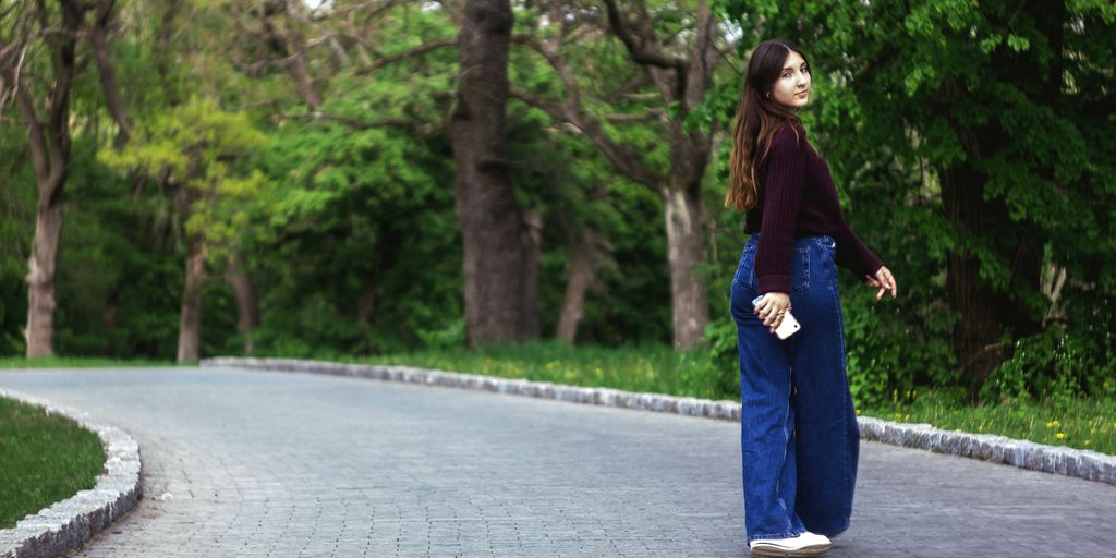 woman in blue denim jeans standing on gray concrete pathway during daytime