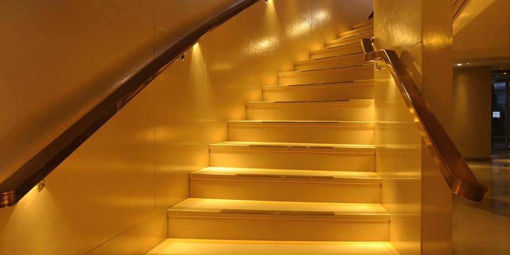Recessed wall lighting illuminating stylish staircase for safety.