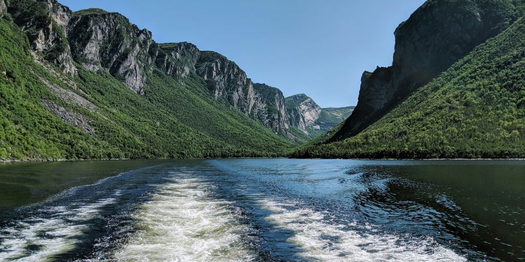 green and gray mountains beside river under blue sky during daytime