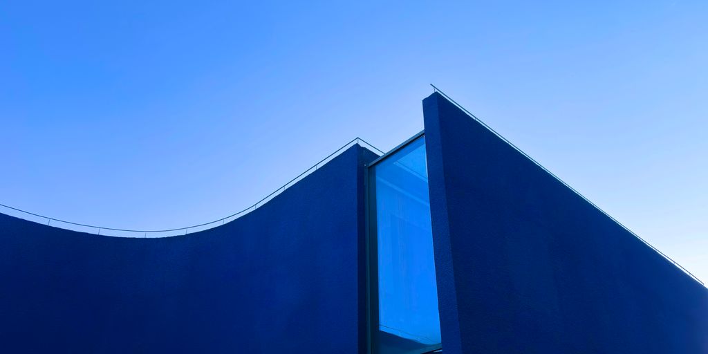 A modern, blue building against a clear sky.