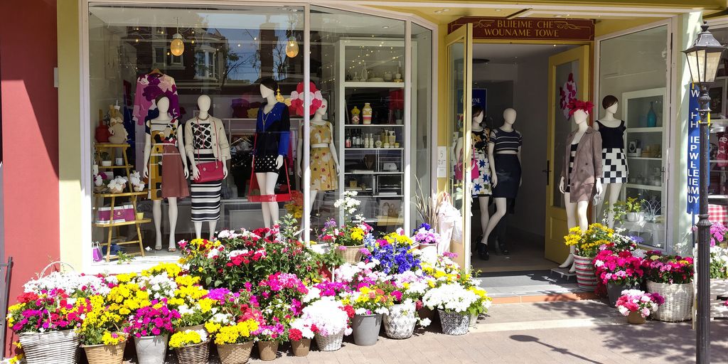 Chic boutique storefront with colorful flowers and stylish mannequins.