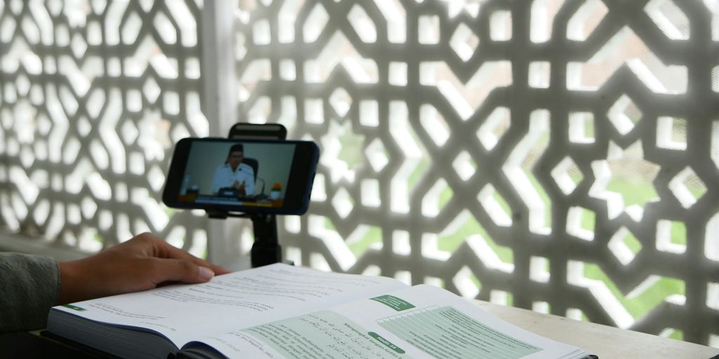 a person sitting at a desk with a book and a cell phone