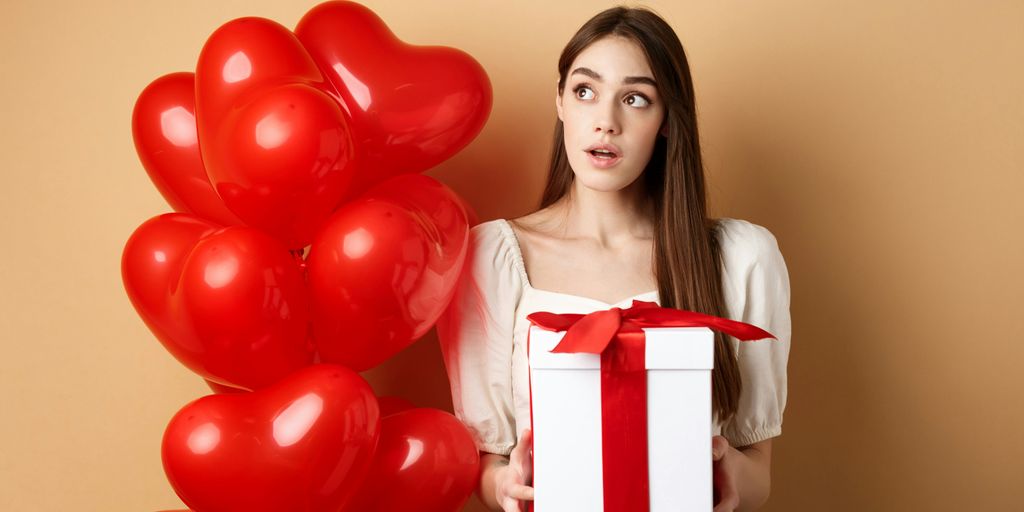 a woman holding a gift box and a bunch of balloons