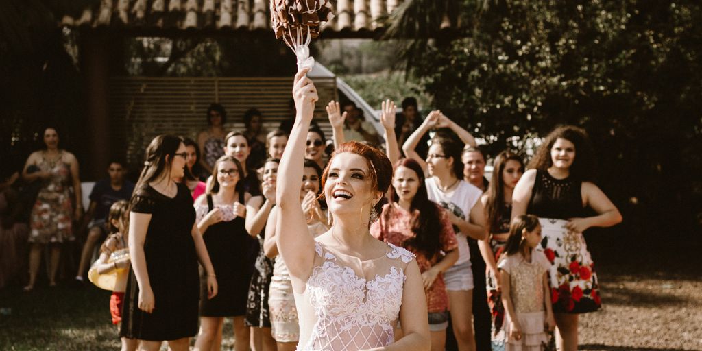 bride throwing flower bouquet on women during daytime
