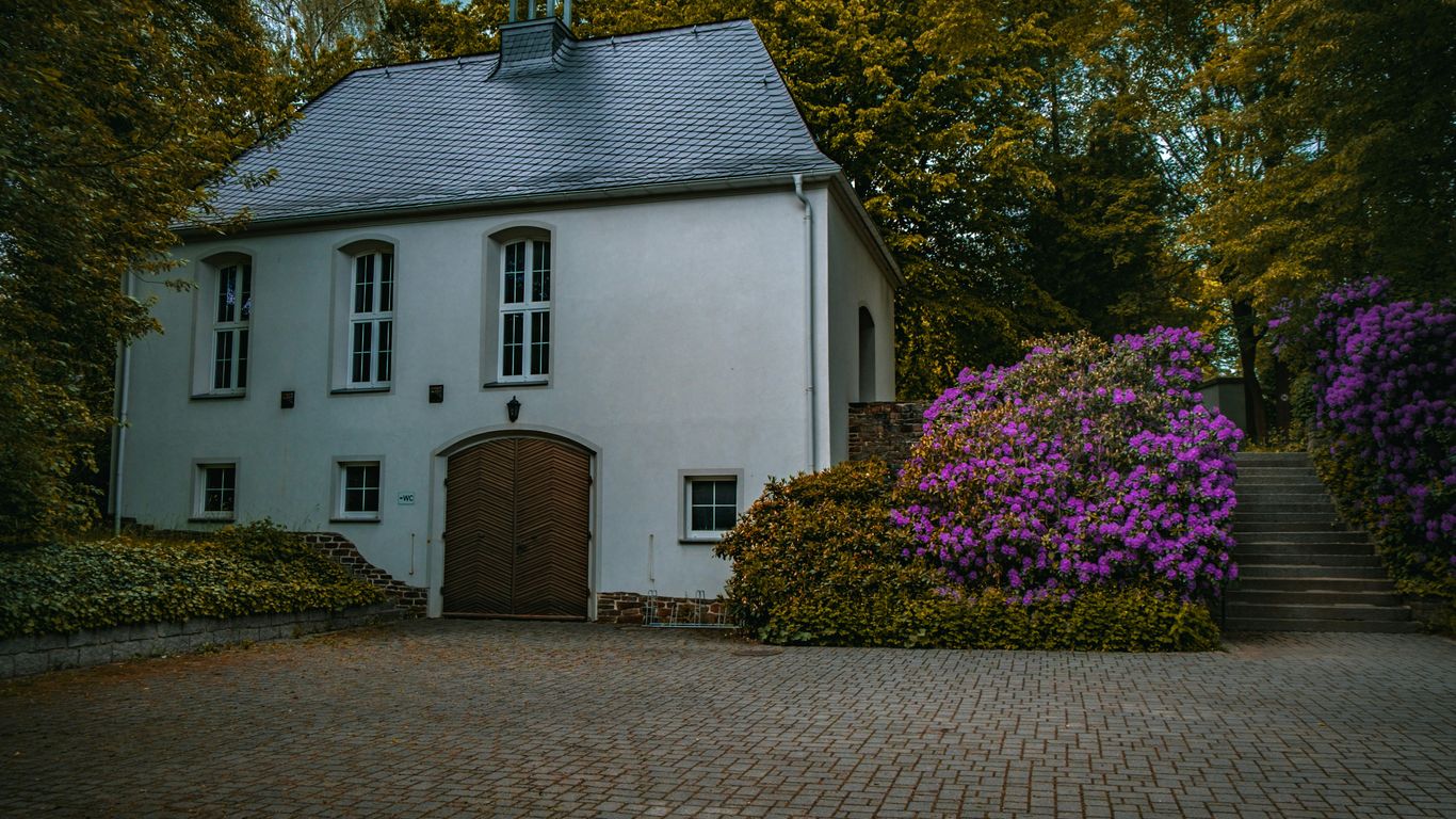 a white house with purple flowers in front of it