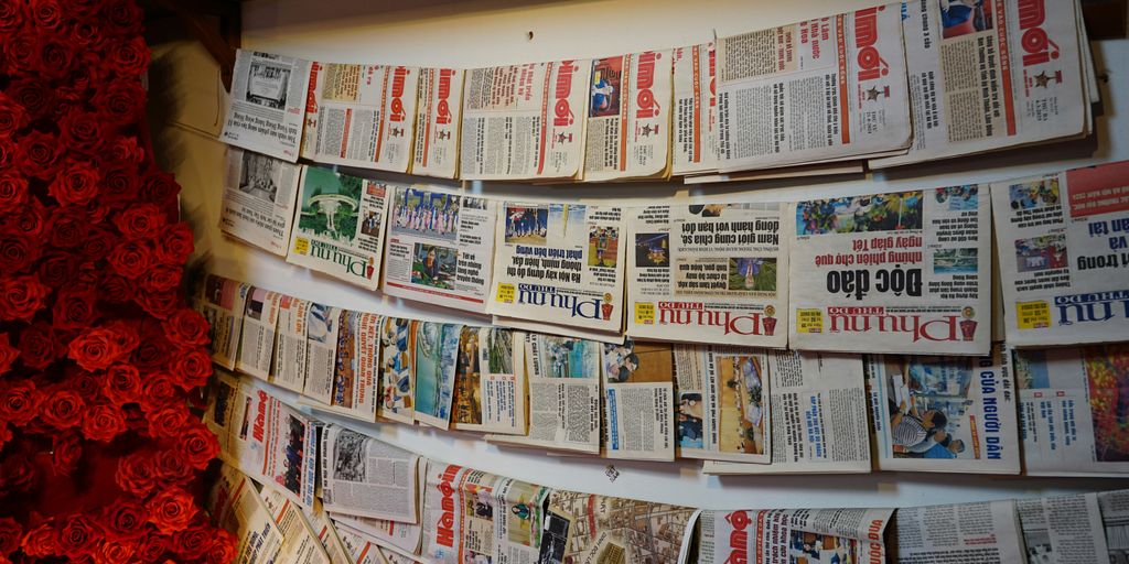 Newspapers pinned to a wall, side view.