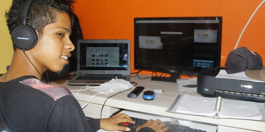 a young man sitting at a desk with headphones on