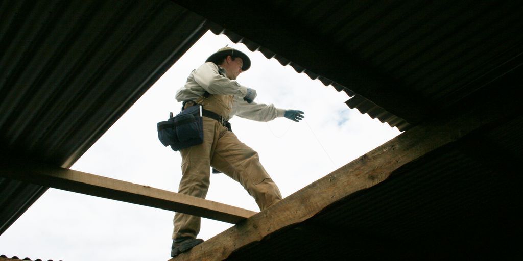 man in gray jacket and brown pants sitting on brown wooden post during daytime
