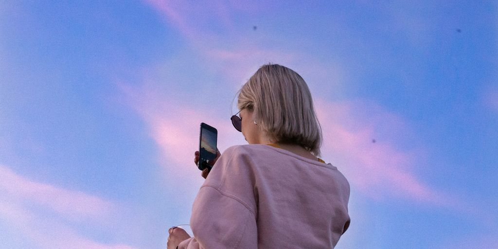 woman in sunglasses and pink top holding phone