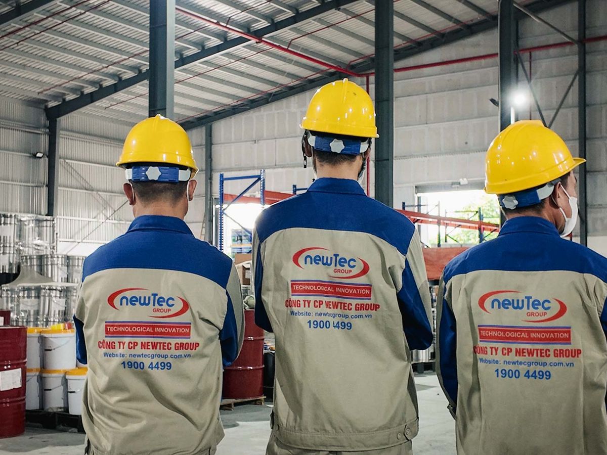 Three individuals in safety gear inside an industrial environment.