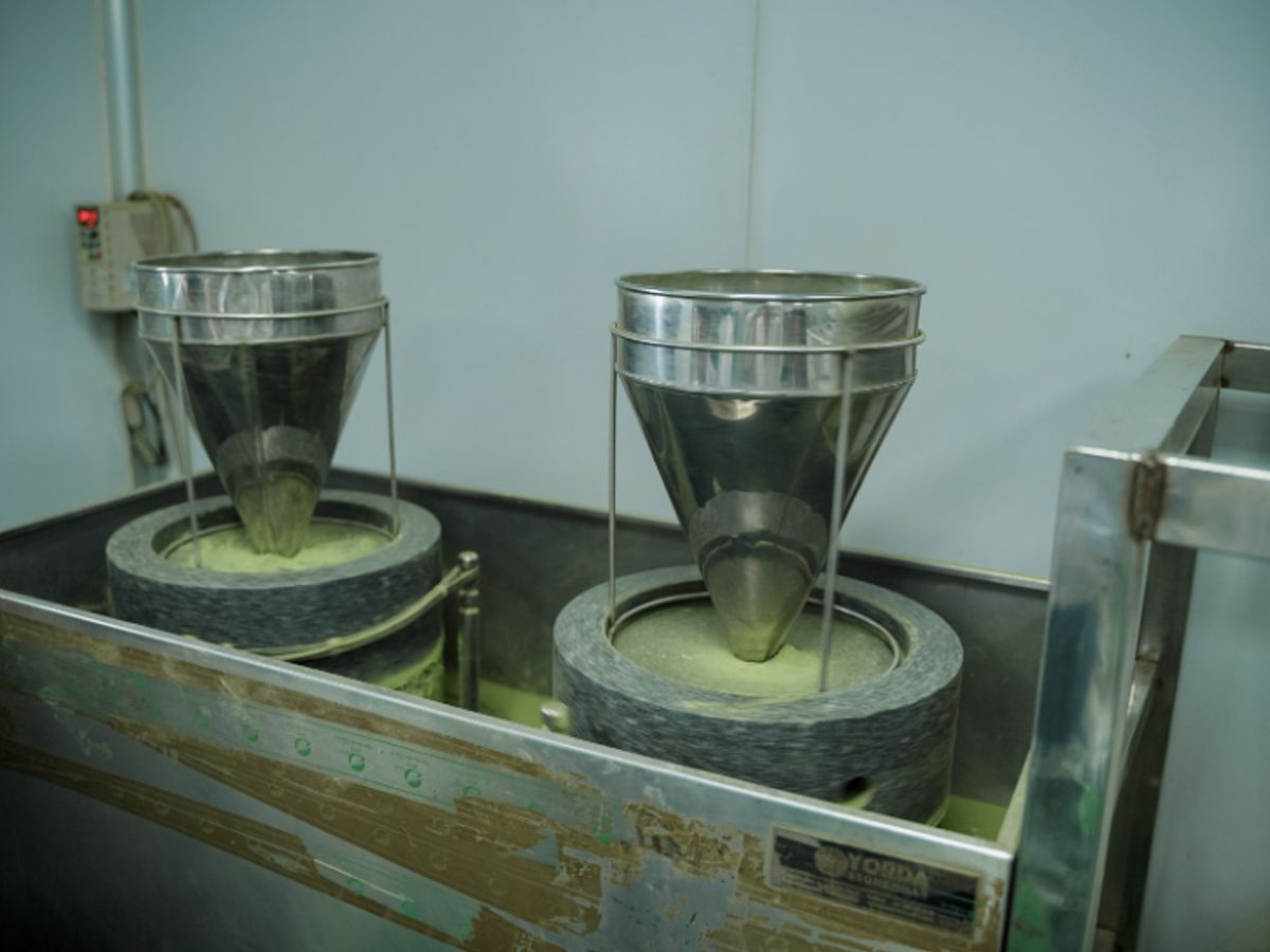 Two metal containers on a machine, likely for grinding food.