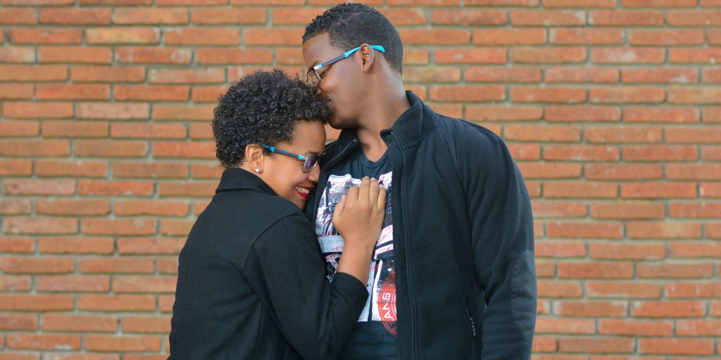 man kissing the forehead of woman