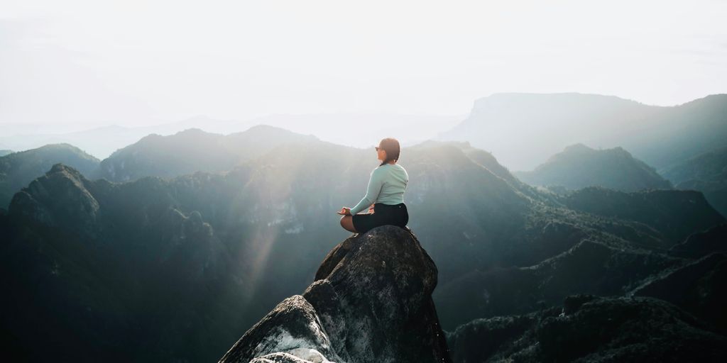 a man sitting on top of a large rock