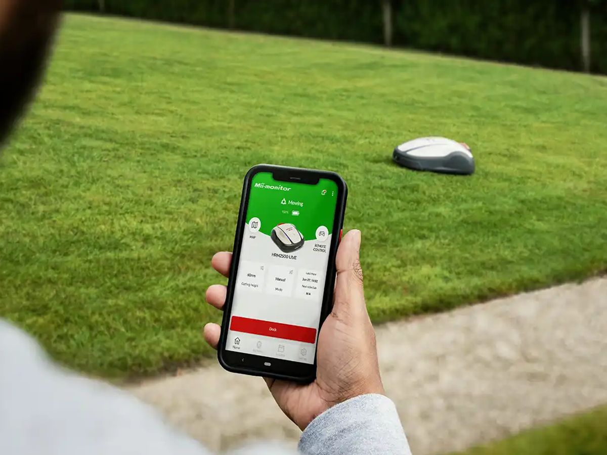 User controlling a robotic lawn mower with a smartphone app.