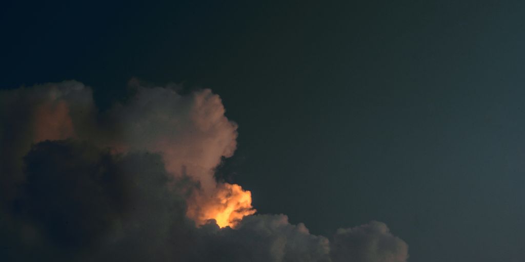 a jet flying through a cloudy sky at night