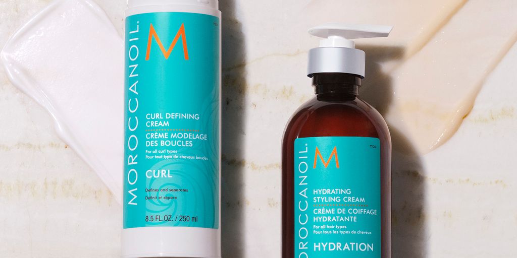 Two bottles of Moroccanoil hair products on a textured surface.