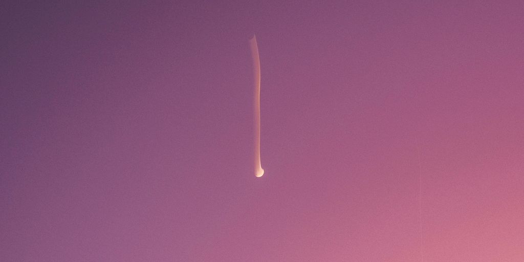 A jet flying through a purple sky next to the ocean