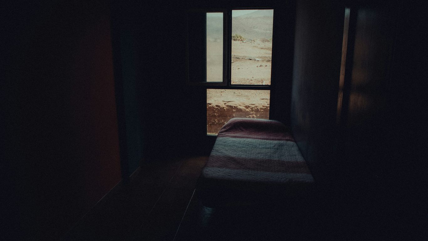 a dark room with a bed and a window