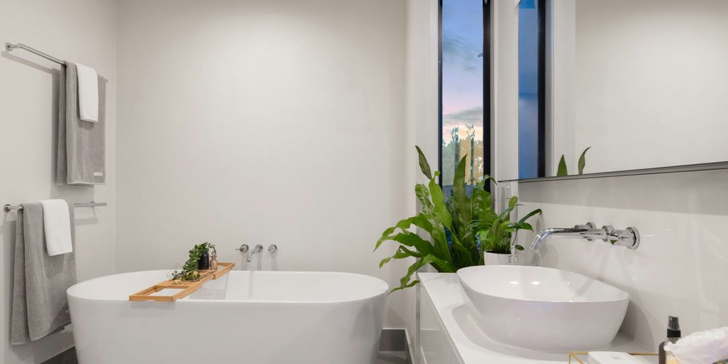 white ceramic bathtub near green potted plant