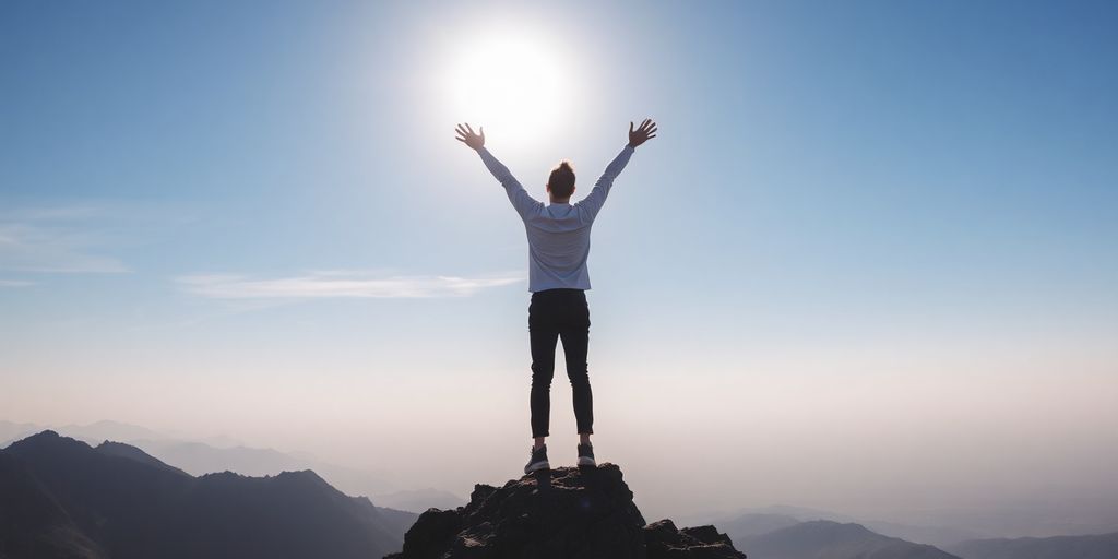 Person celebrating victory on mountain peak under blue sky.