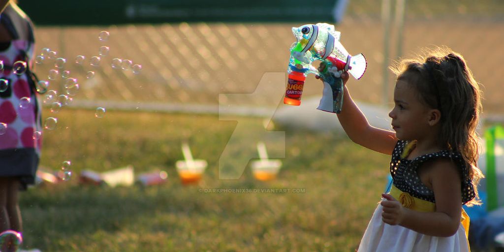 toddler playing with bubble gun toy in park