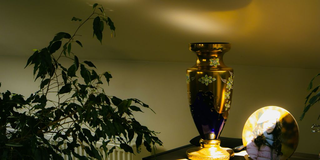 a vase sitting on top of a table next to a plant