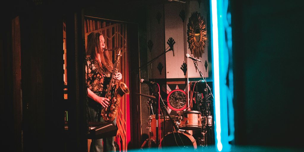 woman playing saxophone on stage near wall clock