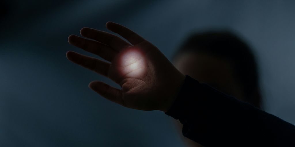 a person holding their hand out in the dark