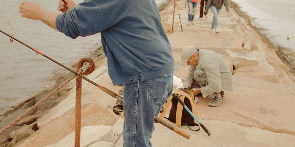 man in blue denim jeans and gray hoodie standing on brown wooden dock during daytime